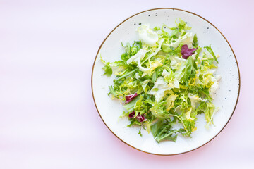 White ceramic plate with fresh salad on light pink background