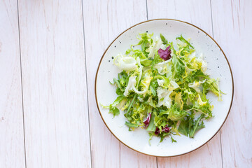 White ceramic plate with fresh salad on wooden background