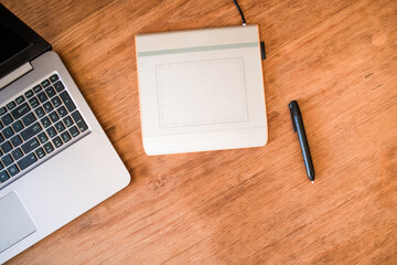 Laptop and graphic tablet on wooden table