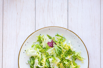 White ceramic plate with fresh salad on wooden background