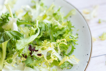 White ceramic plate with fresh salad on wooden background