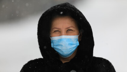 old woman in a black mink coat wearing a medical mask