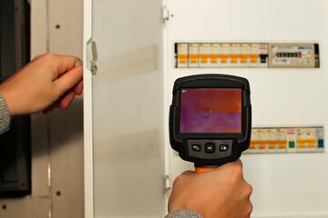 thermal imaging inspection of electrical equipment. Close-up shot of man hand recording heat loss with infrared thermal camera
