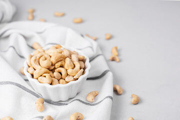 Natural organic raw cashew nuts in white plate on light background, copy space. Basis of norm fats, oils, protein. Keto diet and a healthy snack. Nut oil is a source of vitamins.
