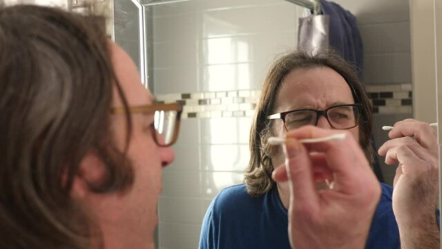Man Inserting the cotton swab too deep in his ear and puncture his ear drum.