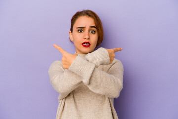 Young arab mixed race woman points sideways, is trying to choose between two options.