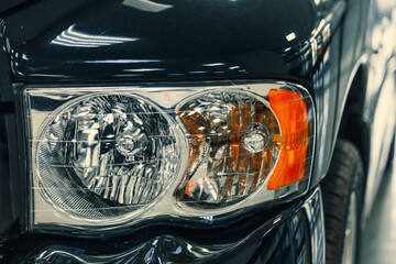 close-up of the front headlights of a retro black car in a showroom or garage