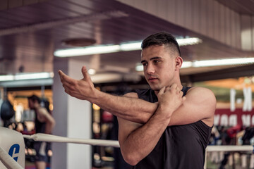 Young handsome kick boxer training hard, stretching and preparing. Fighter working out at gym