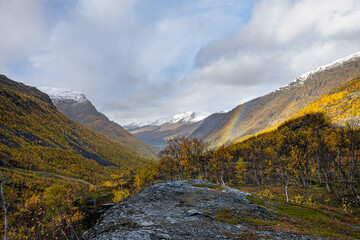 Light rainbow over a valley with dwarf birches