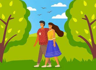 Young married couple is walking in green summer park. Woman wears yellow blouse and blue skirt, man in brown trousers, blue T-shirt hugs girl by the shoulders. Green summer trees, grass, birds flying