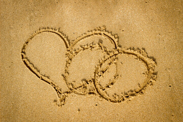 Painted in the sand Heart and two wedding rings.