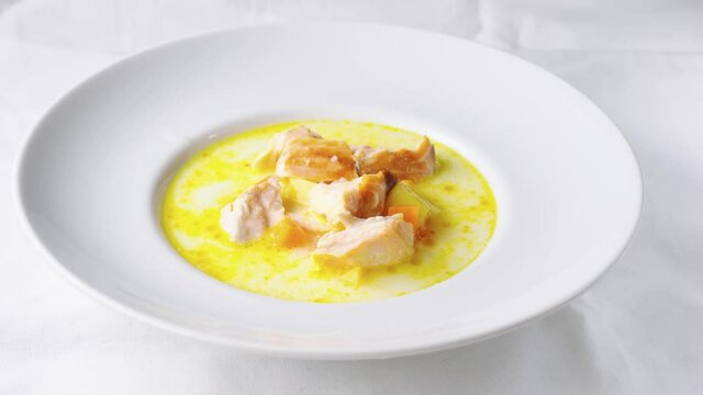Pouring healthy salmon cream soup into white plate