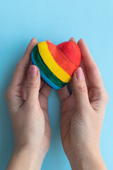 Female hands holding a heart in lgbt colors, free love concept