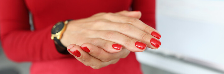 Girl in red clothes shows hands with red manicure. Office employee submits a report