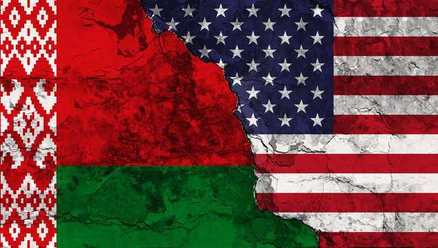 Concept of a Conflict between the United States of America and Belarus with painted flags on a wall with a crack