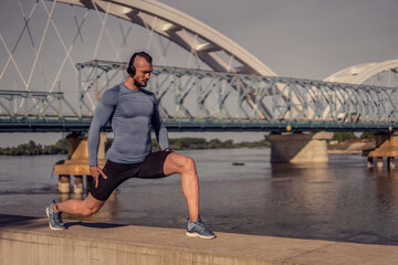 Young handsome man training hard. Man doing sports outside. Outdoors recreation, stretching and training fit body