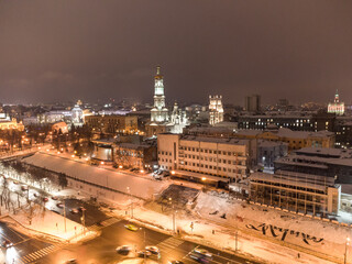 Winter snowy evening lights illuminated city aerial landscape. Dormition Cathedral, Serhiivskyi Maidan in Kharkiv downtown, Ukraine