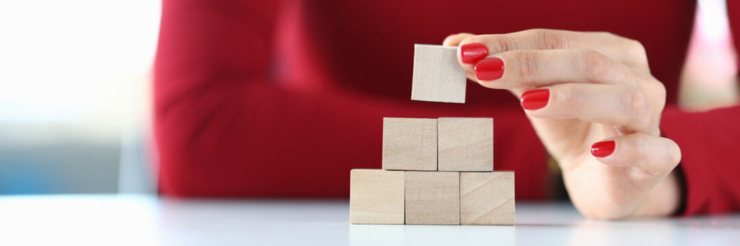 The woman stacks wooden bars on the table. Concept implementation of internal motives
