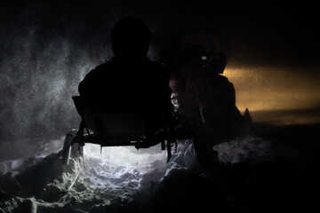 Silhouette of a search and rescue patrol on snowmobile at night during a blizzard.