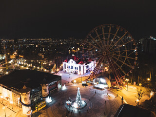 Ferris wheel in Park of Maxim Gorky not working in winter holidays,illumination lights in Kharkiv city center park. Aerial close view at night on city lights streets background