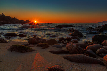 Sunbeams at sunset on a beach with rocks