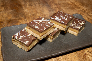 A delicious pile of Millionaires Flapjacks chocolate and toffee sweet treats on a wooden table