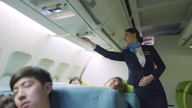 Flight attendance walking and turn off the light during passenger sleeping in the first class of airplane. aAll passenger feel tried and sleepy during trip in nighttime. Travel and holiday concept