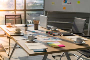 closeup meeting table and chairs with laptop , paper  and coffee cup, conference room in modern office with glass windows 