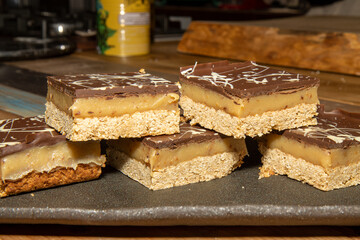 A delicious pile of Millionaires Flapjacks chocolate and toffee sweet treats on a wooden table