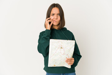 Fototapeta premium Young hispanic traveler woman holding a map with fingers on lips keeping a secret.