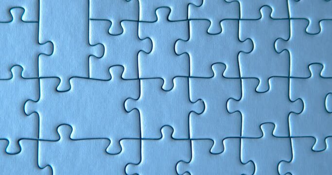 Gray puzzles stacked on blue background. Female hand is putting down one piece. Finishing, completion of work task. Successful achievement of goal. Decision, solution of problem, issue found.