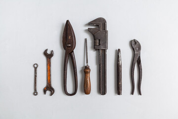 Old tools with a patina, arranged as a diagram, are waiting to be used in the workshop. Pipe wrenches, open-end wrenches, ring spanners and other workshop equipment, plumbing, automotive job expertise
