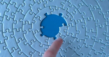 Female hand is putting down gray circular puzzles, pieces, stacking, matching together on blue background. Finishing, completion of work task. Successful achievement of goal. Decision, solution found.