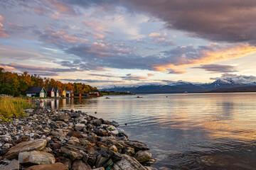 Shore of Troms&oslash; during sunset with mountains in the background