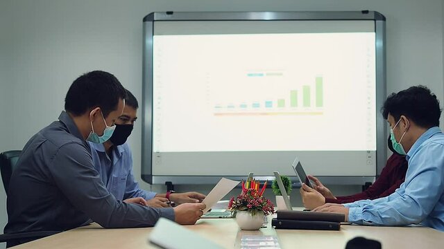Businessmen wearing protective masks discussing and work together in meeting room. Social distance practice prevent coronavirus COVID-19.