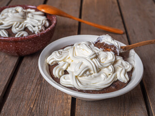 Latvian rye soup dessert with whipped cream in a deep plate on a wooden background