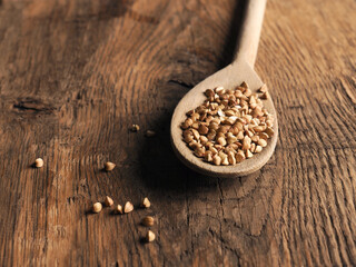 Organic buckwheat on a wooden spoon on a wooden kitchen table