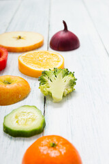 sliced fruit and vegetable circles on white wood table
