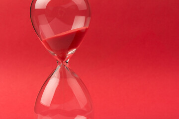 Crystal hourglass on pink and red background as a concept of passing time for business term, urgency and outcome of time.