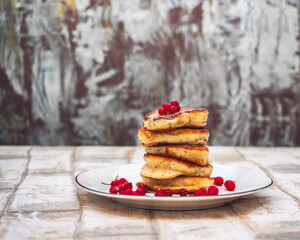 Stack of homemade pancakes with red currant berries on white plate