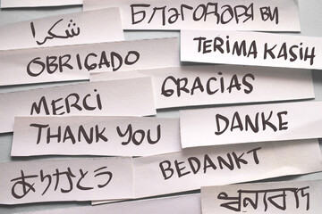 Thank you in different languages, text words typography written on paper against blue background,...