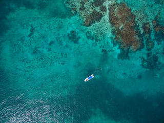 Drone shot of a boat floating near the coral reef barrier Cancun Sardinia rent boat for tourism in...