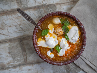 Soup with vegetables and meatballs seasoned with sour cream and a spoon