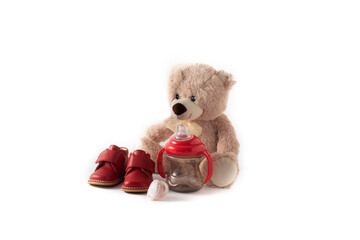 Teddy bear, pacifier,feeding bottle and shoes isolated on white background