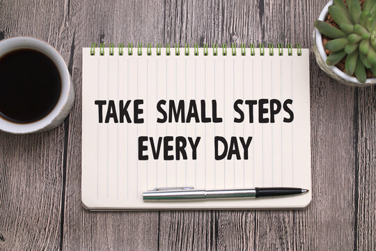 Take small steps every day, text words typography written on book against wooden background, life and business motivational inspirational