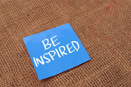 Be inspired, text words typography written on  paper against wooden background, life and business motivational inspirational