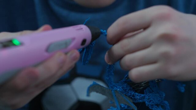 a young man makes a 3 d model with a pen. dragon model made of plastic wire.