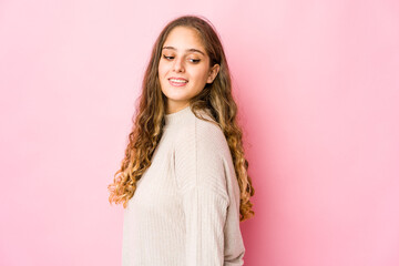Young caucasian woman looks aside smiling, cheerful and pleasant.