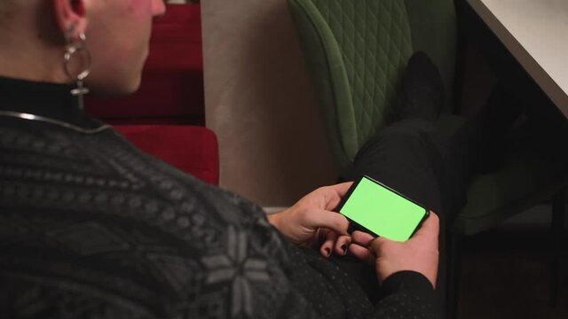 Close up homosexual man with a manicure holding chromakey green screen smartphone watching content, swiping scrolling, video call chatting. Gadgets people concept.