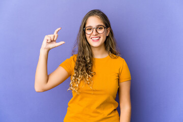 Fototapeta premium Young caucasian cute woman holding something little with forefingers, smiling and confident.